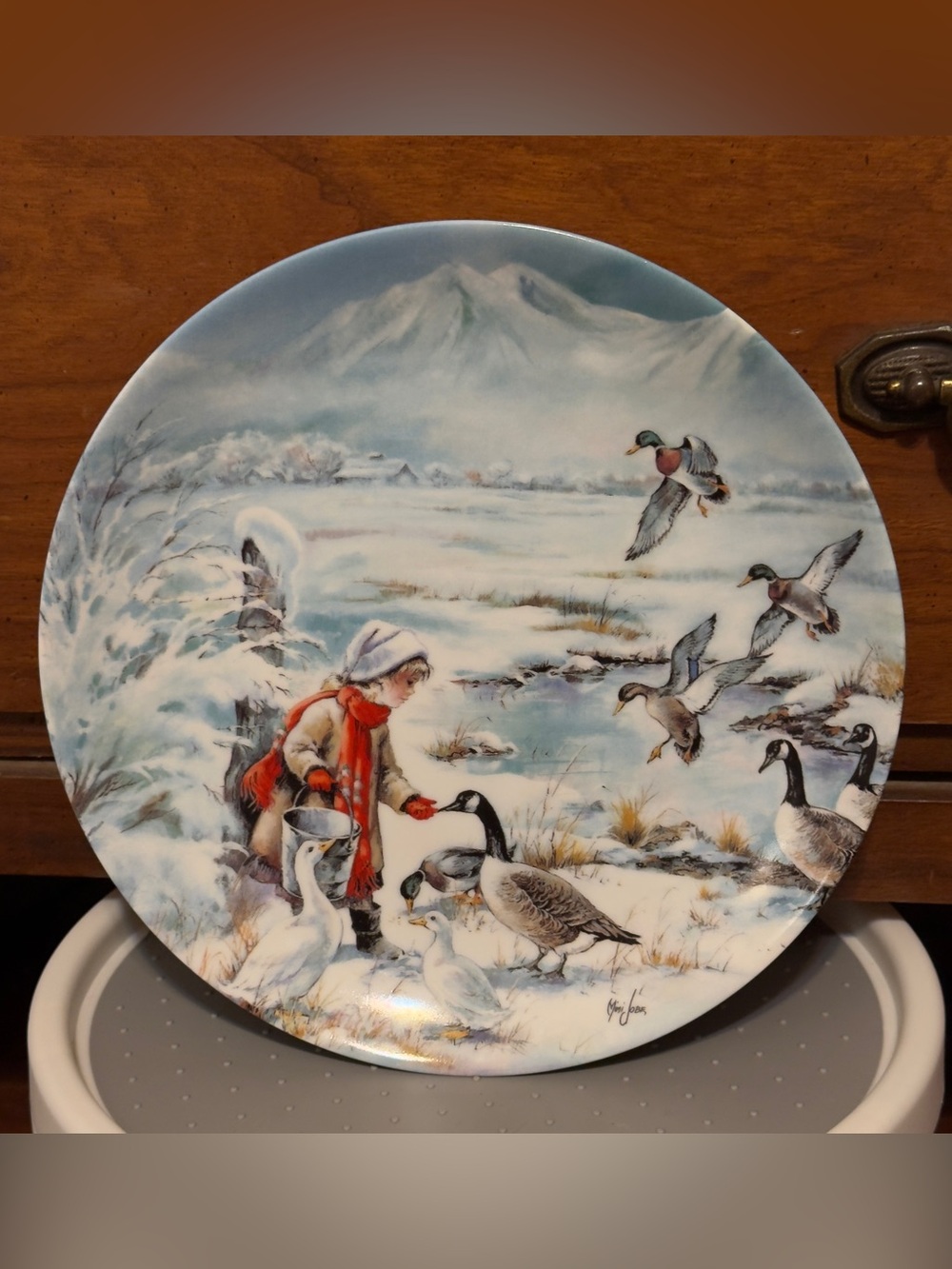 A decorative porcelain collector plate by Mimi Jobe, "Sharing."